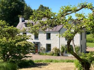 una casa bianca con alberi in primo piano di Bedrule Old Manse B&B a Hawick