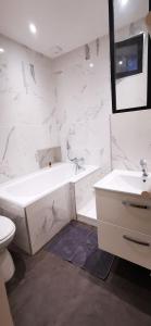a white bathroom with a tub and a sink at Maison cocooning au cœur du centre historique in Fougères