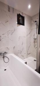 a white bathroom with a tub and a tv on the wall at Maison cocooning au cœur du centre historique in Fougères +21 photos
