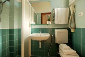 uma casa de banho com um lavatório, um WC e um espelho. em Hotel Oceanic em Rimini