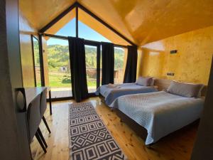 two beds in a room with a large window at Peak Lodge Jyrgalan in Dzhergalan