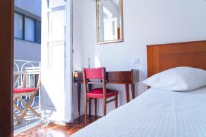 a bedroom with a bed and a desk and two red chairs at Hotel Terra Linda in Viana do Castelo
