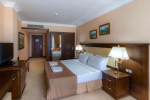 a hotel room with a large bed and a television at Latanya Park Resort in Yaliciftlik