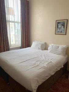 a large white bed in a room with a window at Hotel Balmoral in Bournemouth
