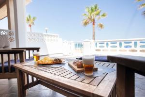 una mesa con una bandeja de comida y dos vasos de cerveza en Chalet Playa Miramar, en Miramar