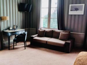 a living room with a couch and a desk and a window at Golf Hotel in Saint-Saëns