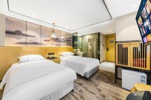 広州市にあるShangyuanHotel Quzhuang Branchのベッド2台とテレビがあるホテルの部屋
