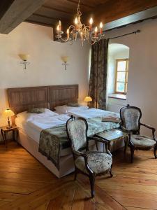1 dormitorio con 1 cama, 2 sillas y lámpara de araña en zámek Kolštejn - hotel Chateau Goldenstein en Branná