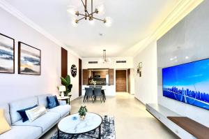 a living room with a white couch and a large tv at GOODWOOD SUITES HOMES VACATION in Dubai