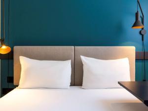 a bed with white pillows and a blue wall at Ibis Marseille Centre Prefecture in Marseille