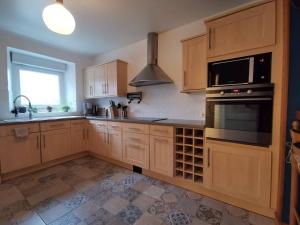 a kitchen with wooden cabinets and a stove top oven at Gîte Le Petit Bacchus in Sainte-Croix-Hague