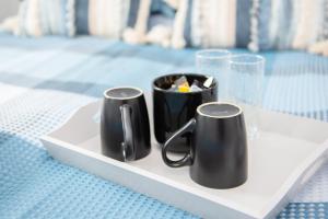 two black mugs on a white plate on a table at Parade School Guest Rooms in Berwick-Upon-Tweed
