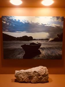 a picture of a boat on the beach with a rock at Afrodite Hotel Apartments in Myrina