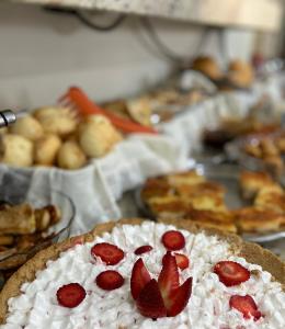 a cake with strawberries on top of it with other pastries at HOTEL GUAIRACÁ in Guarapuava