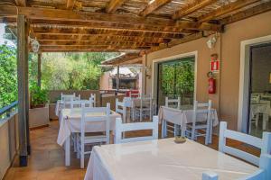 a restaurant with white tables and white chairs at Hotel L'Oleandro in Villasimius