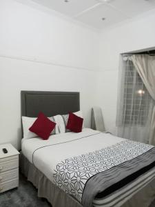 a bedroom with a bed with red pillows and a window at Linze lodge in Durban