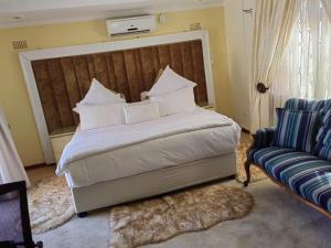 a bedroom with a large bed and a chair at Obaa Sima Guest House in Mthatha