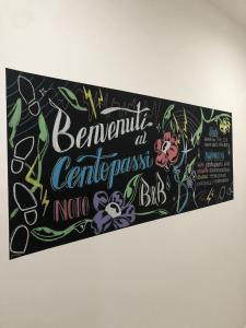 un cartello per un bar con dei fiori sopra di Centopassi Noto B&B a Noto