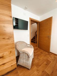 een woonkamer met een rieten stoel en een flatscreen-tv bij Patteriol Lodge in Sankt Anton am Arlberg