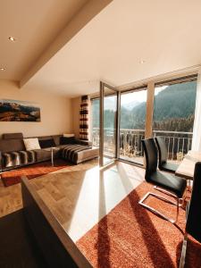 een woonkamer met een bank, een tafel en stoelen bij Patteriol Lodge in Sankt Anton am Arlberg