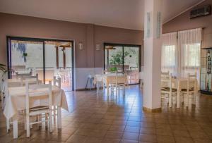 a dining room with white tables and chairs at Hotel L'Oleandro in Villasimius