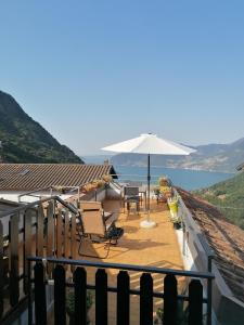 eine Terrasse mit einem Sonnenschirm, einem Tisch und Stühlen in der Unterkunft Casa vacanze 'La piazza' in Zone