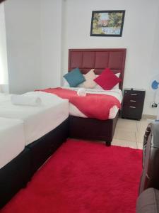 a bedroom with two beds and a red rug at Linze lodge in Durban