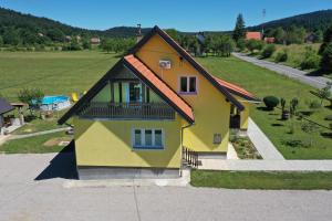 a yellow and orange house with a balcony at Apartman Vito Saborsko in Saborsko