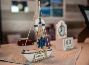 a small toy boat on a table with a clock at Hotel L'Oleandro in Villasimius