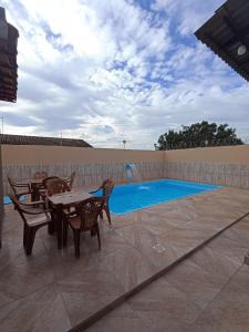 eine Terrasse mit Tisch und Stühlen neben einem Swimmingpool in der Unterkunft Casa linda caldas novas in Caldas Novas