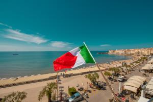 a flag on a beach with the ocean at Hotel Riva Del Sole in Cefalù