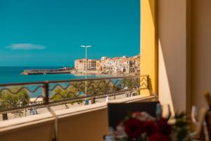 a room with a balcony with a view of the beach at Hotel Riva Del Sole in Cefalù