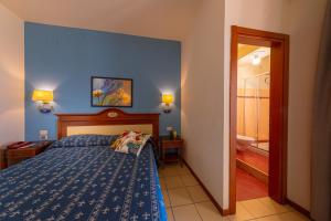 a blue bedroom with a bed and a bathroom at Hotel Riva Del Sole in Cefalù