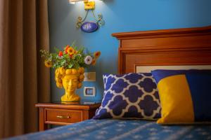 a bedroom with a bed with a vase with flowers in it at Hotel Riva Del Sole in Cefalù