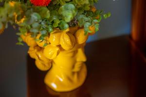 a yellow vase with a plant in it at Hotel Riva Del Sole in Cefalù
