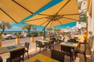 a restaurant with tables and chairs and umbrellas at Hotel Riva Del Sole in Cefalù