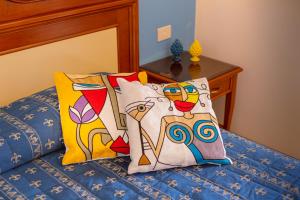 a bed with colorful pillows on top of it at Hotel Riva Del Sole in Cefalù
