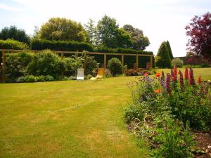 un jardín con césped con flores y un edificio en Stable Lodge B&B, en Petham