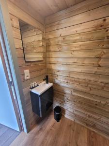 a bathroom with a wooden wall with a sink at Parkhoeve Glamping in Ham