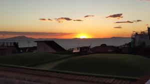 a sunset over a golf course with the ocean in the background at Villino Campagna in Meta