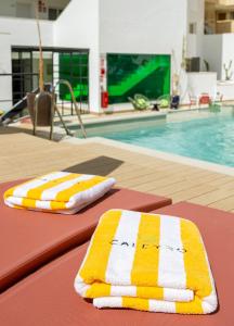 two towels sitting on a table next to a swimming pool at Caleyro Boutique Apartments - "Parking incluido" in Fuengirola