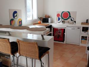 een keuken met witte aanrechtbladen en stoelen bij Robin's Lodge in Vidauban