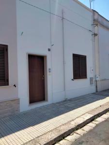 a white building with three windows and a door at Casa Vacanze Lu Trappitu in Magliano