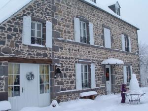 a stone house with snow in front of it at Maison d'Hôtes La Nichée in Rochefort-Montagne