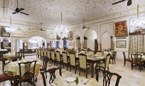 Un comedor con mesas y sillas y una lámpara de araña. en Nahargarh Ranthambhore, en Sawāi Mādhopur
