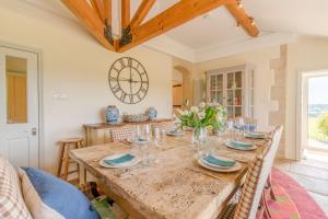 een eetkamer met een houten tafel en een klok aan de muur bij Ivy Cottage in Chippenham