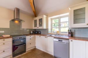 una cocina con armarios blancos y fregadero en Ivy Cottage, en Chippenham