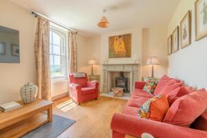 a living room with a red couch and a fireplace at Ivy Cottage in Chippenham