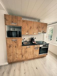 uma cozinha com armários de madeira, uma pia e um micro-ondas em Studio Sarah em De Panne