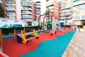 a playground with slides and play equipment on a red carpet at Global Properties, Bonito apartamento en Urbanizacion Ciudad Mar in Puerto de Sagunto